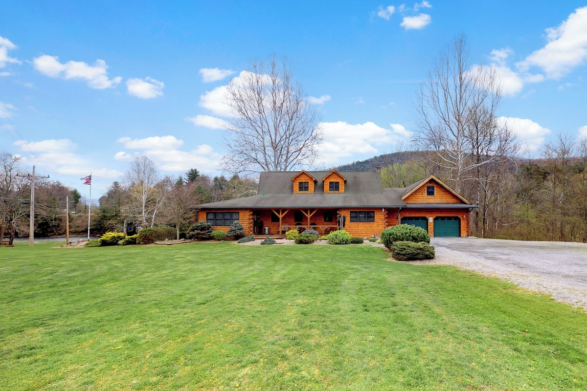 A log cabin with a large front porch, a garage, and a well-maintained lawn.