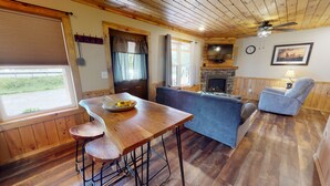 A cozy living room with a wooden dining table, blue sofa, and a fireplace.