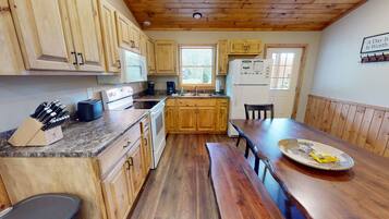 A kitchen with wooden cabinets, a granite countertop, a dining table, and a bench.