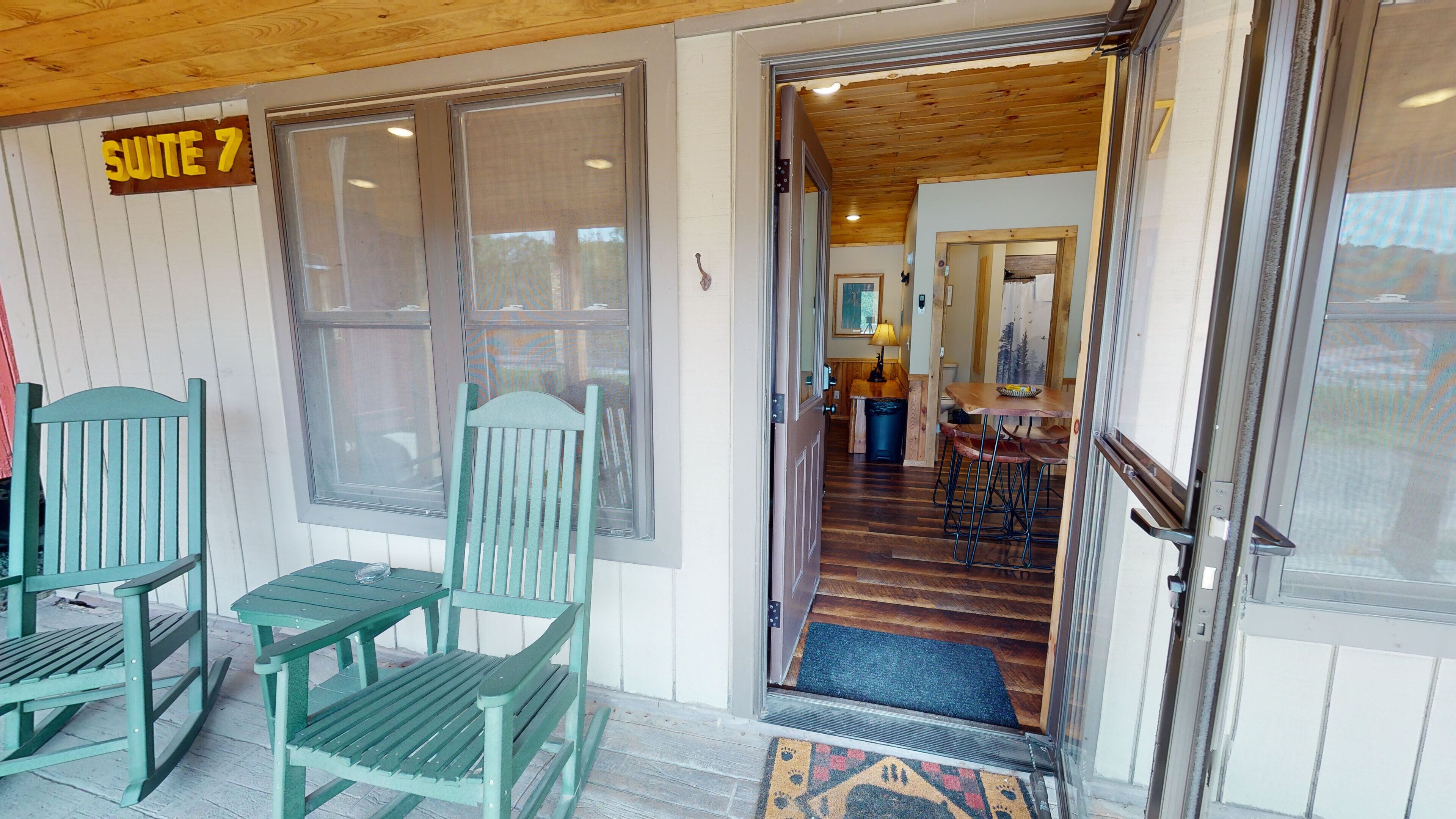 A wooden interior with a sign for 'SUITE 7' and a dining area with a table and chairs.