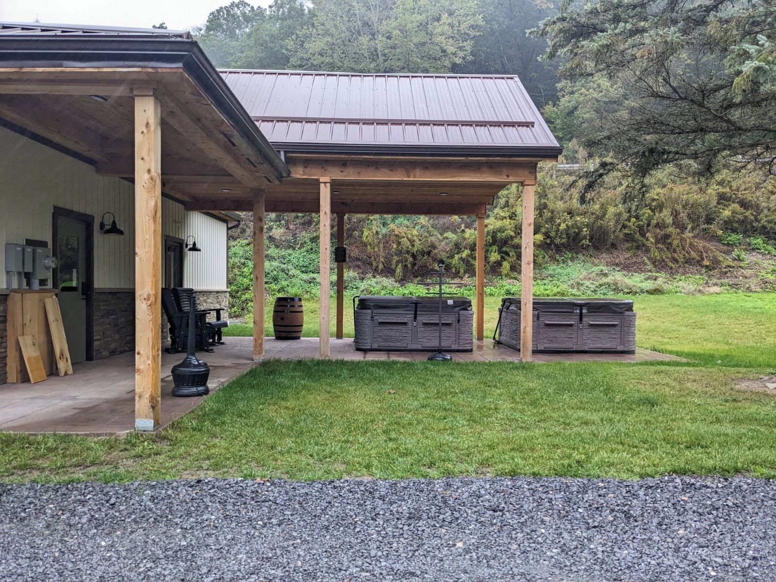 Ein überdachter Außenbereich mit einer Holzkonstruktion, einem Grill und Stauräumen.