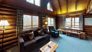 A cozy cabin interior with a sofa, armchair, and wooden table.