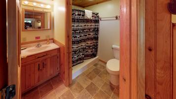 A bathroom with wooden cabinets, a sink, a toilet, and a shower curtain with animal prints.