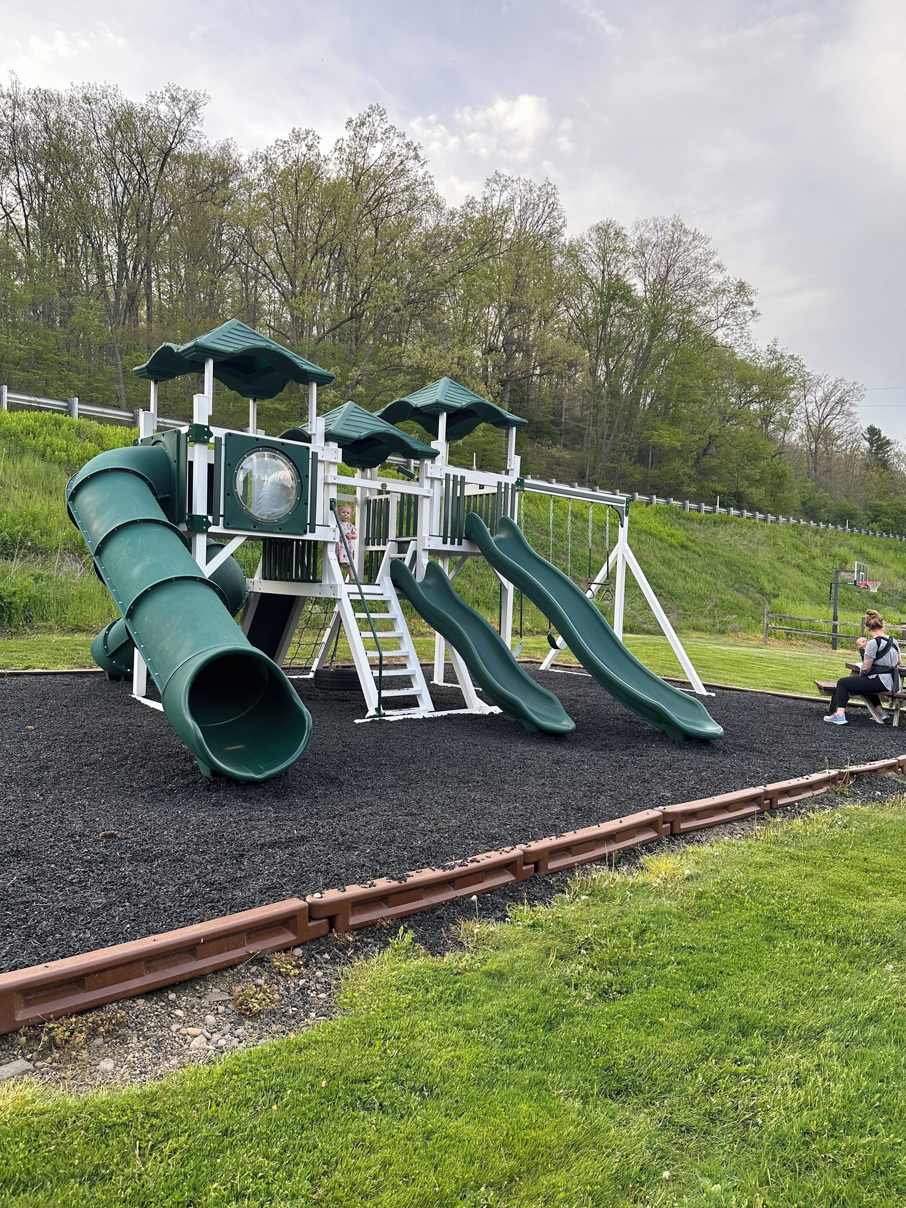 Une aire de jeux avec des toboggans verts et une structure d’escalade.