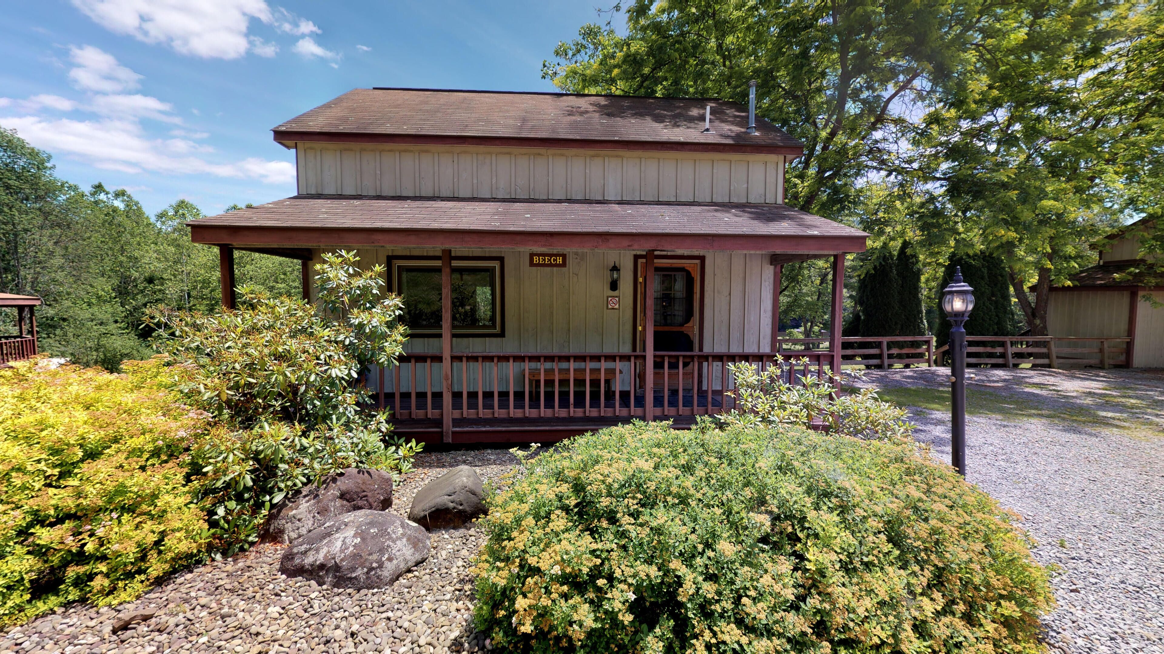 A two-story building with a porch, a sign reading "BEECH," and a gravel pathway leading to it.