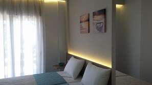 Ein Hotelzimmer mit einem großen Bett, einem Nachttisch mit einer Schale und zwei an der Wand befestigten Bildern.