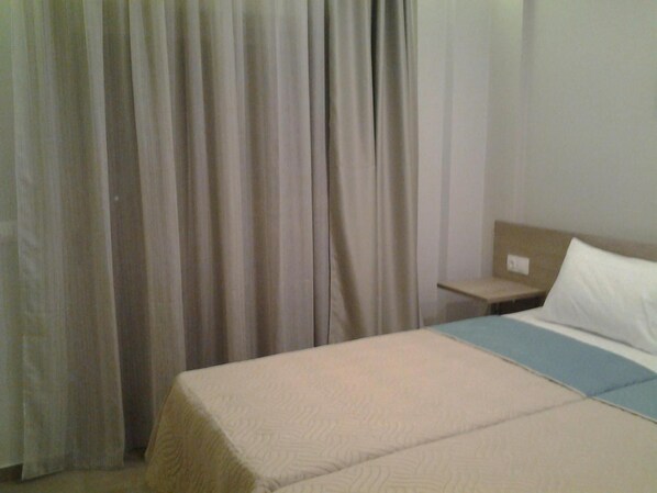 Una habitación de hotel con una cama, una mesita de noche y una ventana con cortinas.