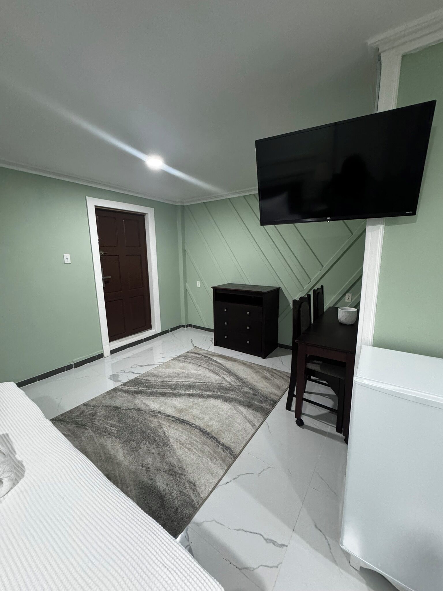 Una camera da letto con un letto, una scrivania, una sedia, una televisione e un armadio.