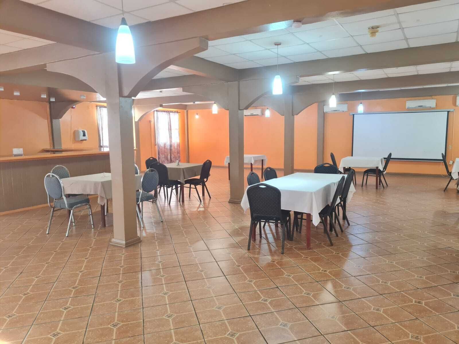 A conference room with multiple tables and chairs, a whiteboard, and a projector screen.
