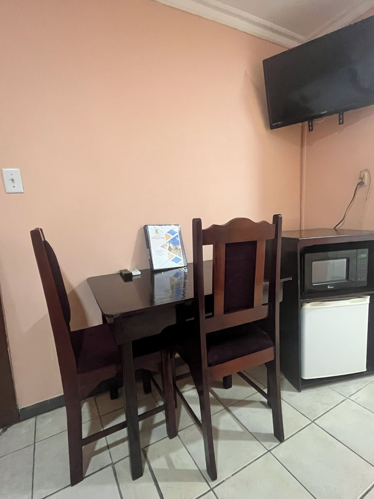 Un petit coin repas avec une table et deux chaises, un four à micro-ondes et un téléviseur fixé au mur.