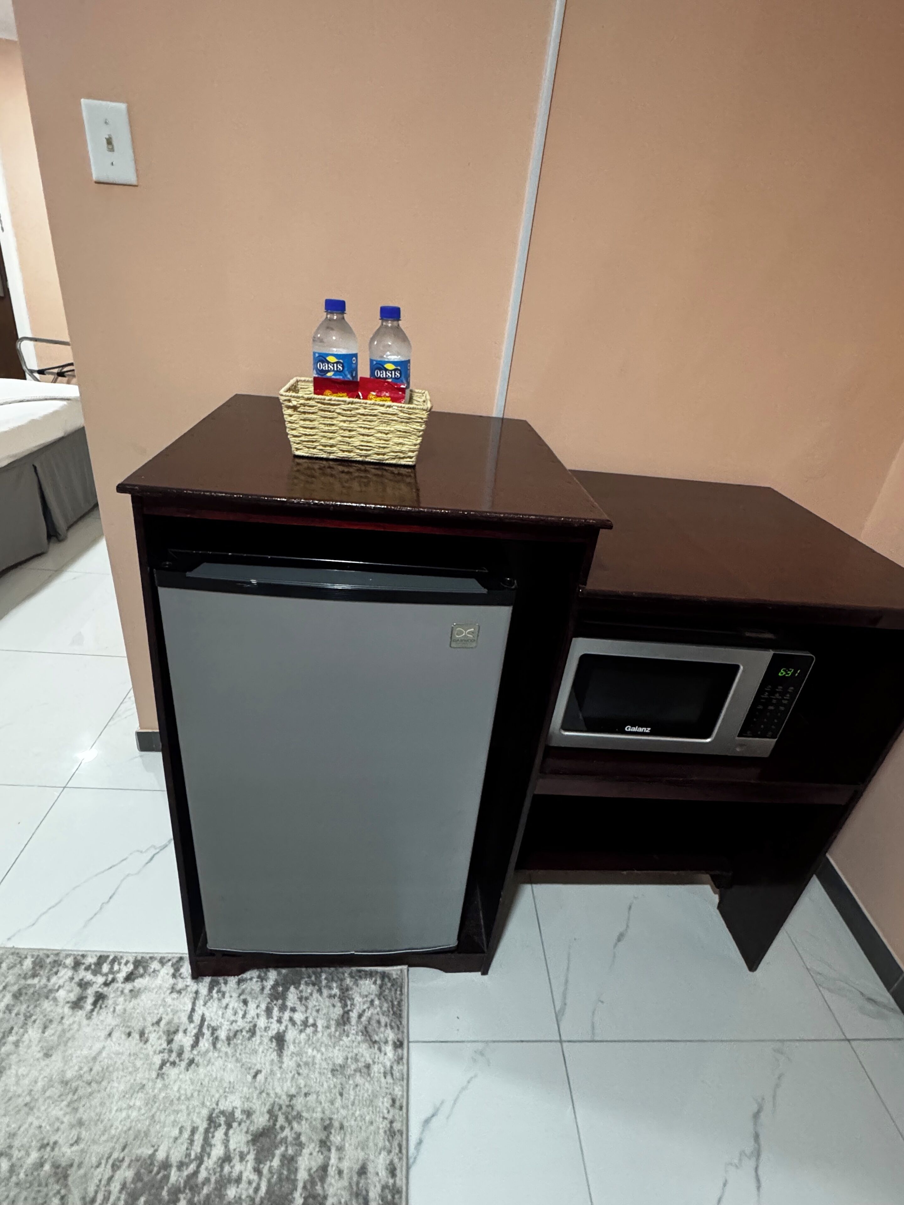 Une petite cuisine équipée d’un réfrigérateur, d’un four à micro-ondes et d’une petite table avec des bouteilles d’eau.