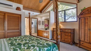 Ein Schlafzimmer mit Himmelbett, Holzmöbeln und einem großen Fenster mit Blick auf Bäume.