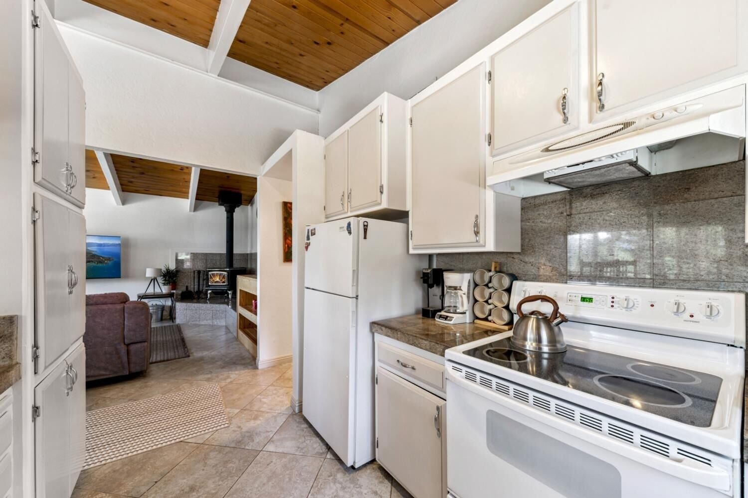 A compact kitchen with white cabinets, a stove, and a refrigerator.