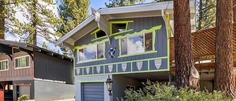A two-story house with a garage, surrounded by trees.