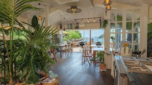 A spacious indoor area with wooden flooring, multiple tables and chairs, and large windows offering a view of the outdoors. - Hansan Marina Hotel & Resort (Tongyeong)