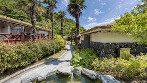 A pathway leading to a building with a stone wall and a small pond. - Hansan Marina Hotel & Resort (Tongyeong)