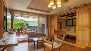 A spacious room with a wooden floor, a large window offering a view of the outdoors, a seating area with a sofa and chairs, and a traditional Japanese sliding door. - Hansan Marina Hotel & Resort (Tongyeong)