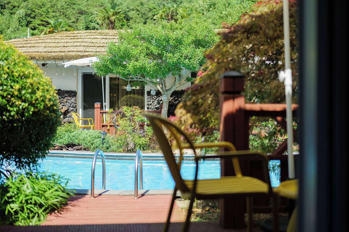 A pool area with chairs and a building in the background.