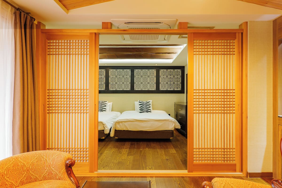 A traditional Japanese-style room with tatami flooring, a low wooden bed, and sliding shoji screens.
