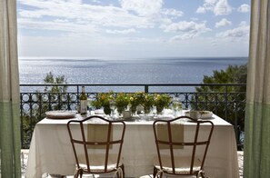 A table set for two with a view of the sea, a balcony railing, and a tablecloth. - Avra Private Suites (Kefalonia)