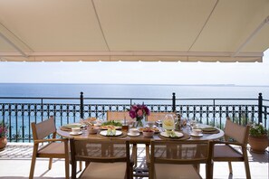 A table set for a meal with a view of the sea, surrounded by chairs and a railing. - Avra Private Suites (Kefalonia)