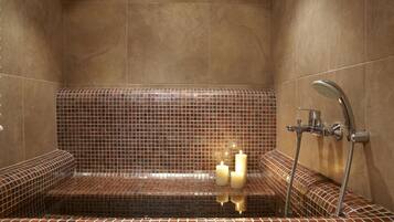 Relax in a spacious tub surrounded by a mosaic-patterned wall and two benches.