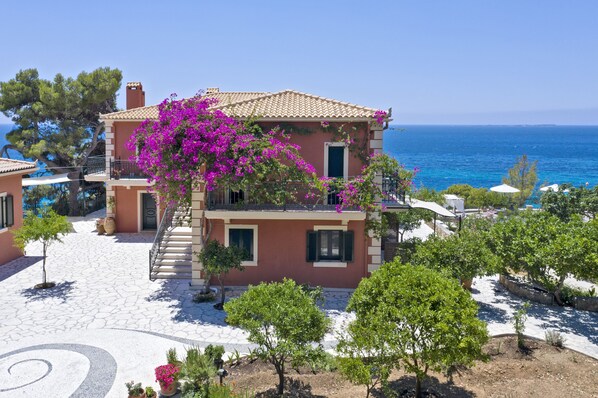 Una vila de estil mediterrani amb teulada de teules, un pati empedrat i vistes al mar.