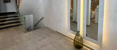 A spacious interior with a staircase, a large mirror, and a decorative vase.