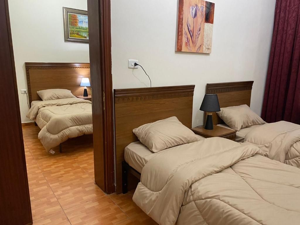 Une chambre d’hôtel avec deux lits, des têtes de lit en bois, une table de chevet avec une lampe et un tableau au mur.