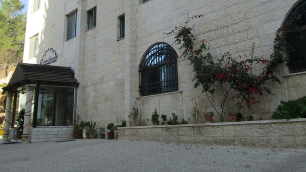 A multi-story building with a central entrance, air conditioning units, and potted plants.