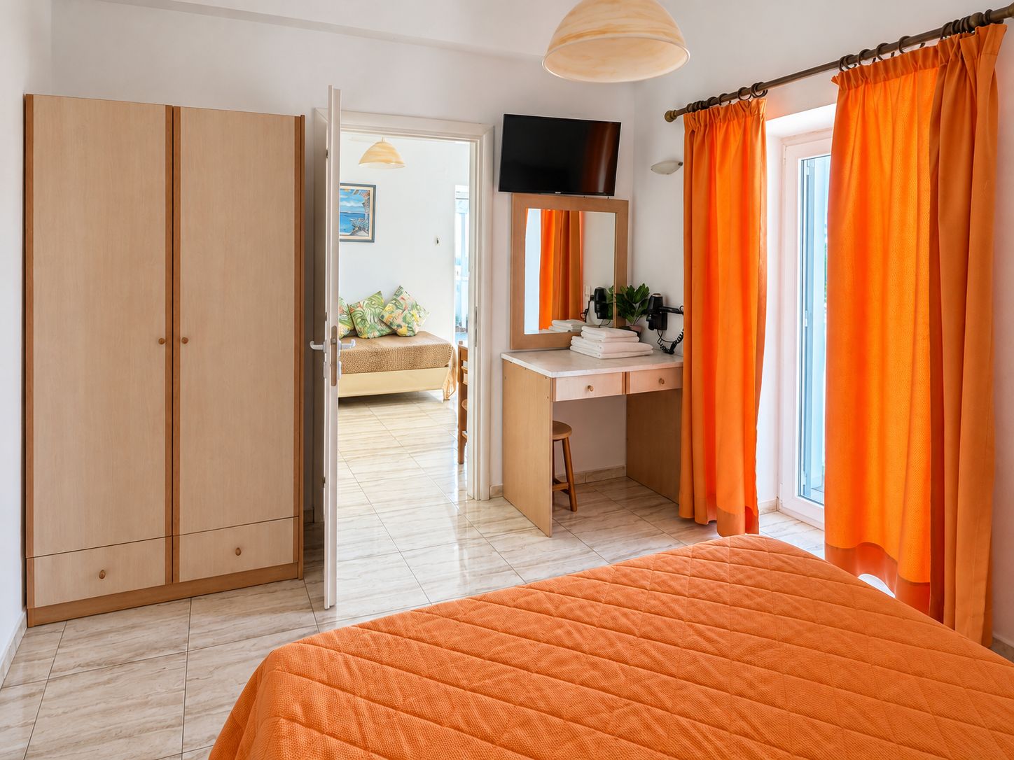 A bedroom with a bed, a desk, and a wardrobe.