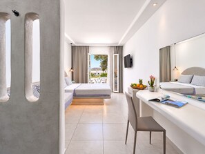 A modern hotel room with a balcony, a bed, a desk, and a TV. - Sofia Village (Mykonos)