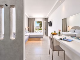 Una habitación de hotel moderna con balcón, cama, escritorio y televisor.