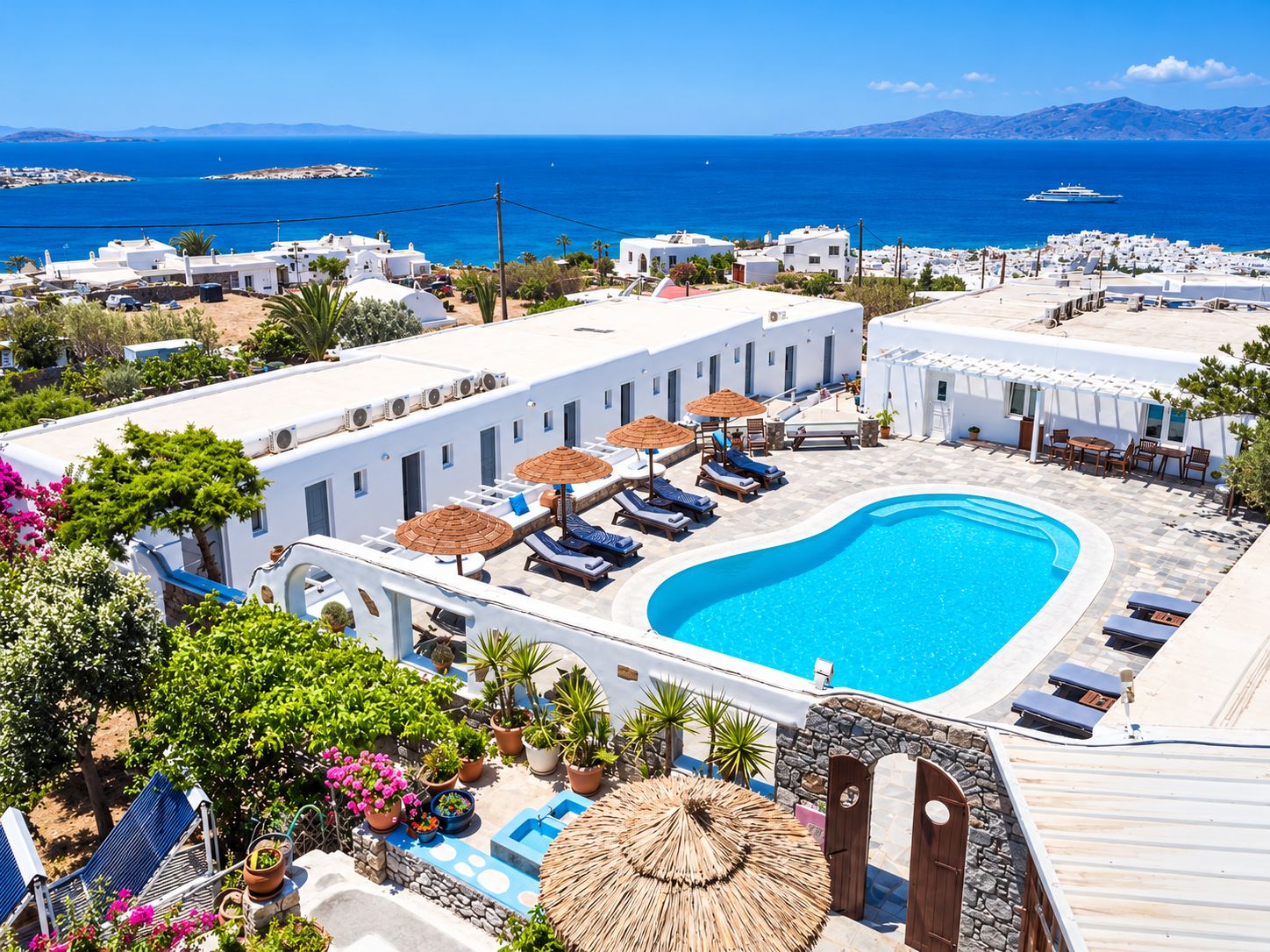 A resort with a swimming pool, sun loungers, and a view of the sea.