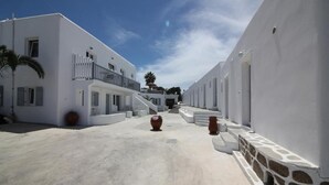A white building with a balcony and steps leading to a door. - Sofia Village (Mykonos)
