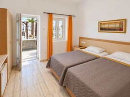 Habitación de hotel con dos camas, un cuadro en la pared y vistas a través de una puerta abierta.