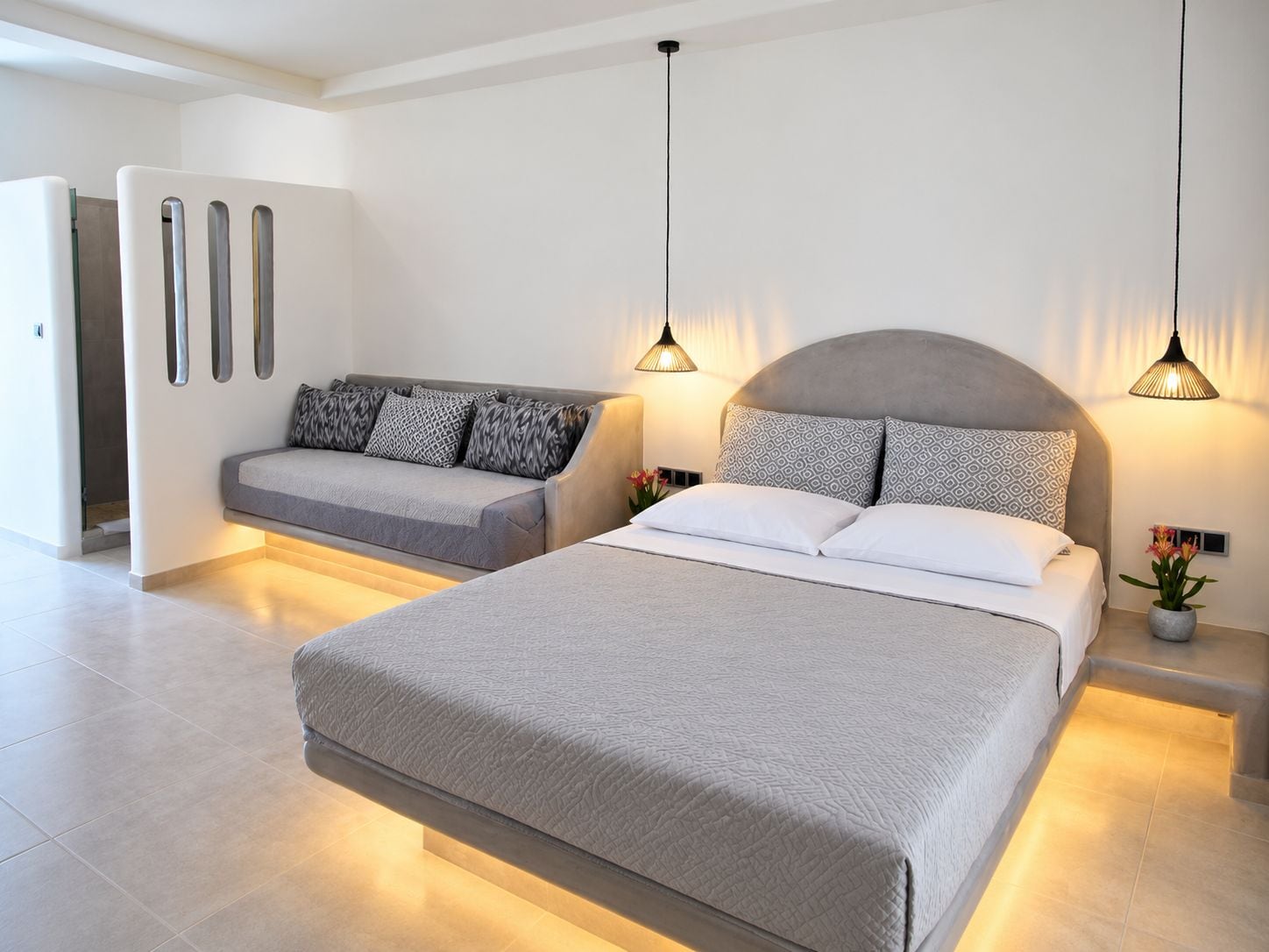 Un dormitorio moderno con una cama grande, un sofá y lámparas colgantes.