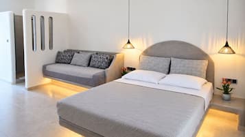 Un dormitorio moderno con una cama grande, un sofá y lámparas colgantes.