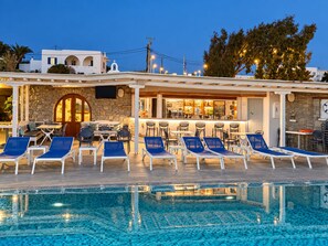 A poolside area with lounge chairs and a bar. - Sofia Village (Mykonos)