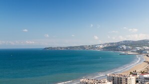 A coastal view with a beach, ocean, and buildings. - Hilton Garden Inn Tanger City Center (Tangier)