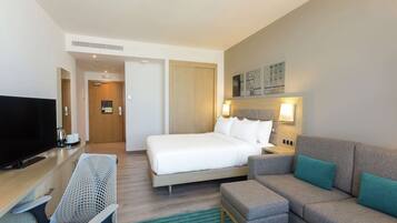 Una habitación de hotel con cama, televisión, escritorio, silla y sofá.