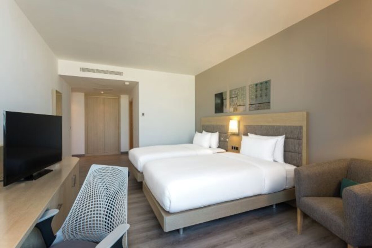 A hotel room with two beds, a TV, and a desk.