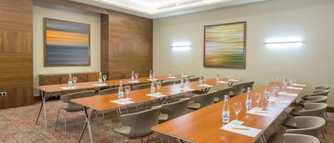 A conference room with long tables, chairs, and water bottles.