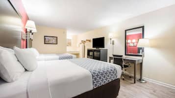 Habitación de hotel con una cama grande, un escritorio con una computadora, un televisor y un espejo.