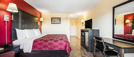 Une chambre d’hôtel équipée d’un lit, d’un bureau, d’une chaise et d’un téléviseur.