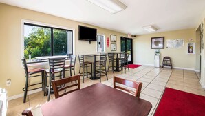 A dining area with a large window, a flat-screen TV, and a red carpet. - Econo Lodge Waynesville (Waynesville)