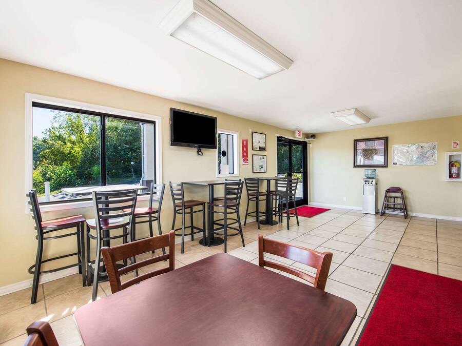 A dining area with a large window, a flat-screen TV, and a red carpet.