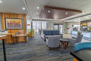 A modern lobby with a reception desk, seating area, and large windows.