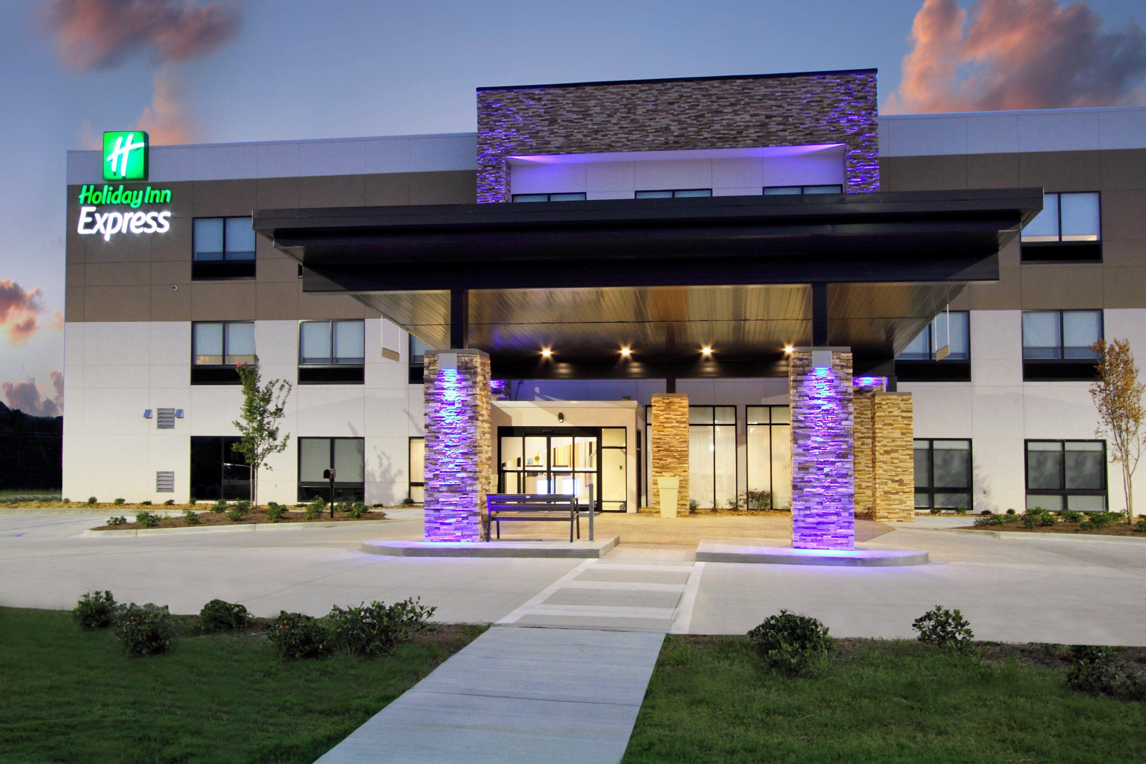 Un hôtel Holiday Inn Express doté d’une façade moderne, d’une entrée abritée et d’un parterre aménagé à l’avant.