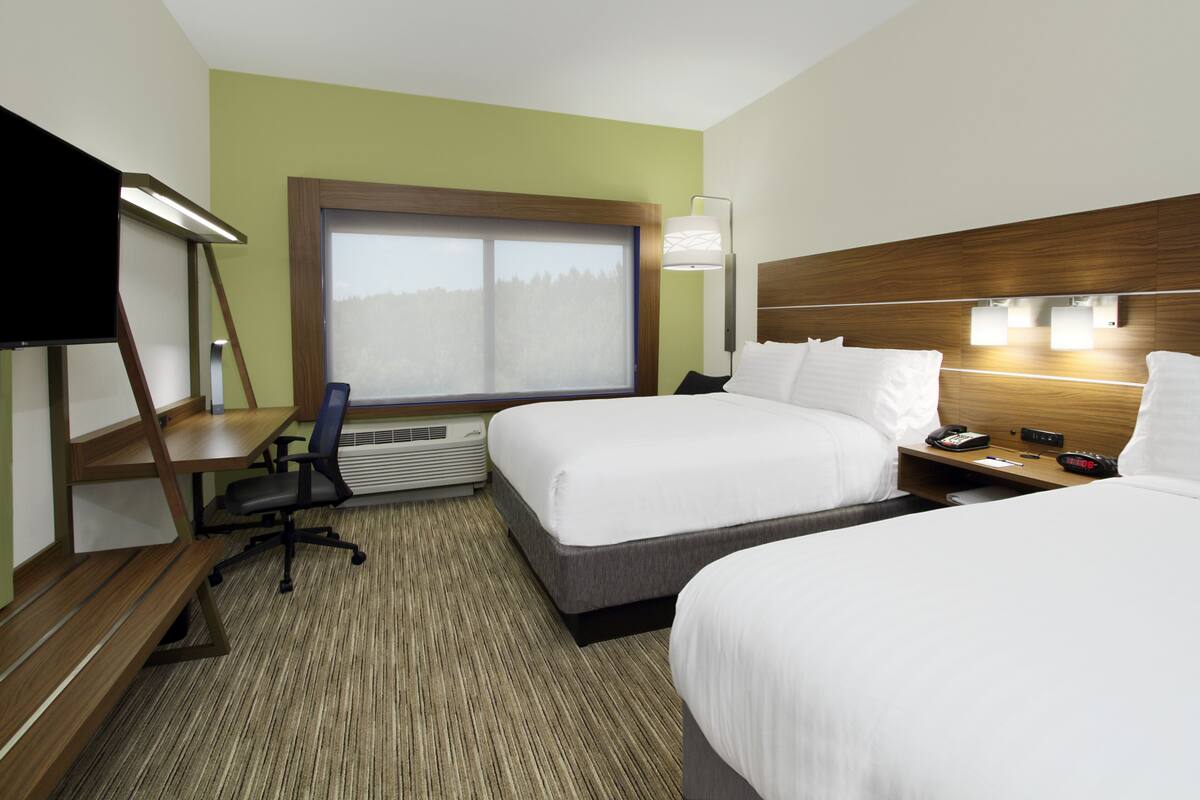 A hotel room with two beds, a desk with a chair, a large window, and a TV.